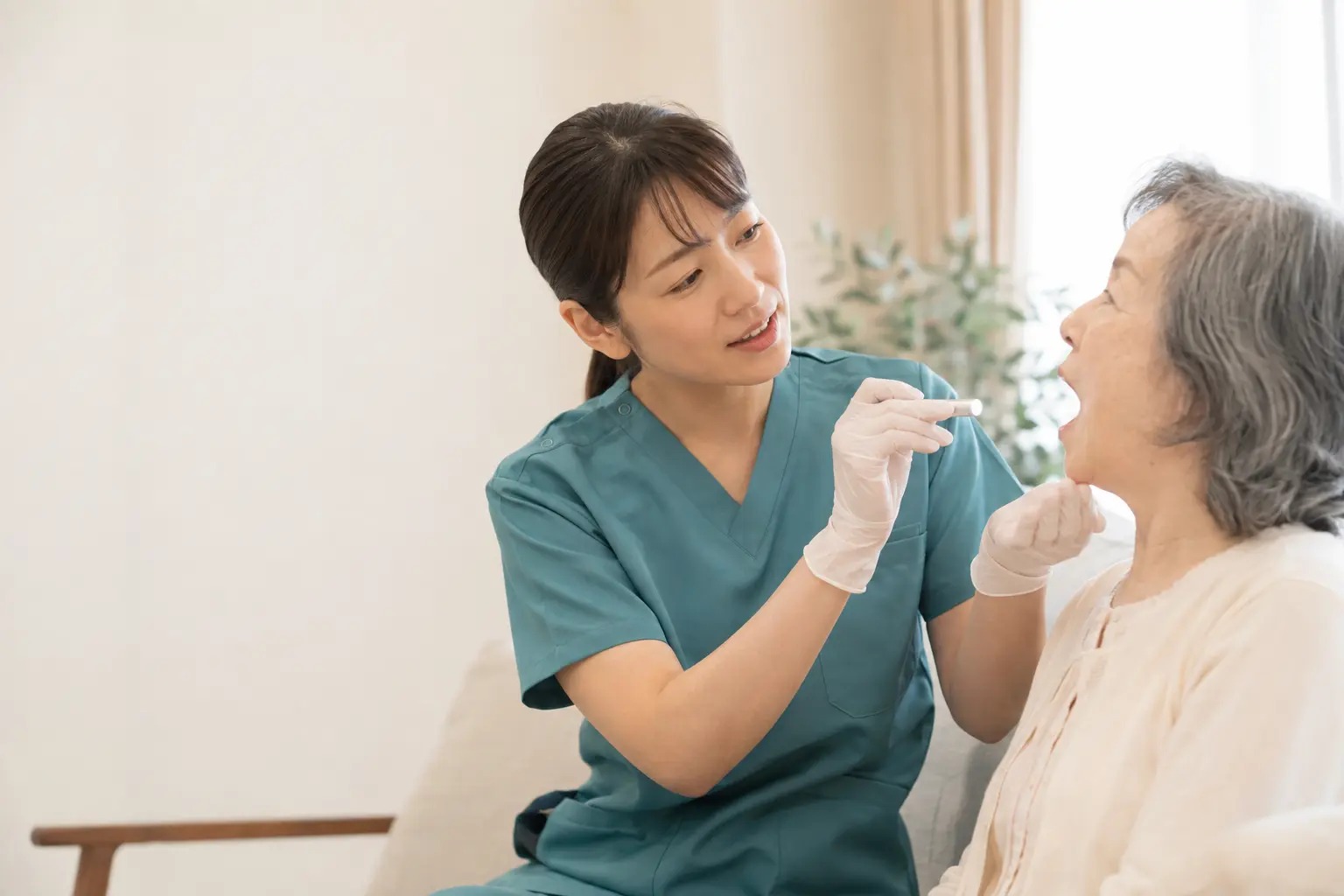 看護師が療養者に声をかけながら口腔状態をやさしく確認する様子